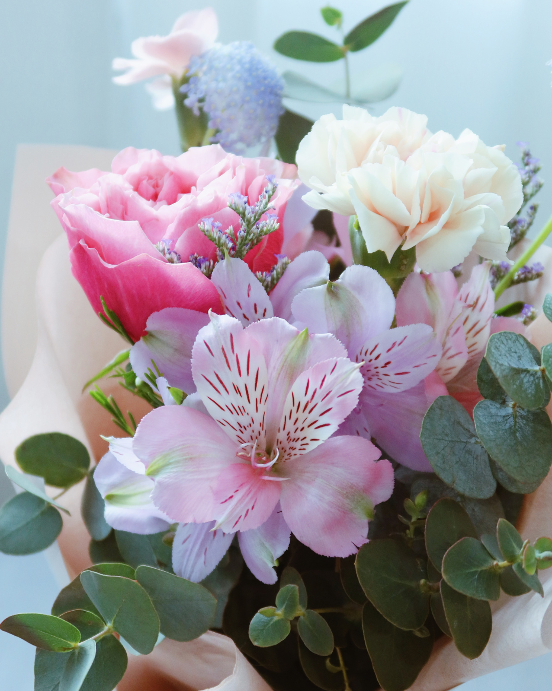 Mother’s Day bouquet with pink garden rose, blush carnations, and blue didiscus – soft, elegant, and full of natural charm.