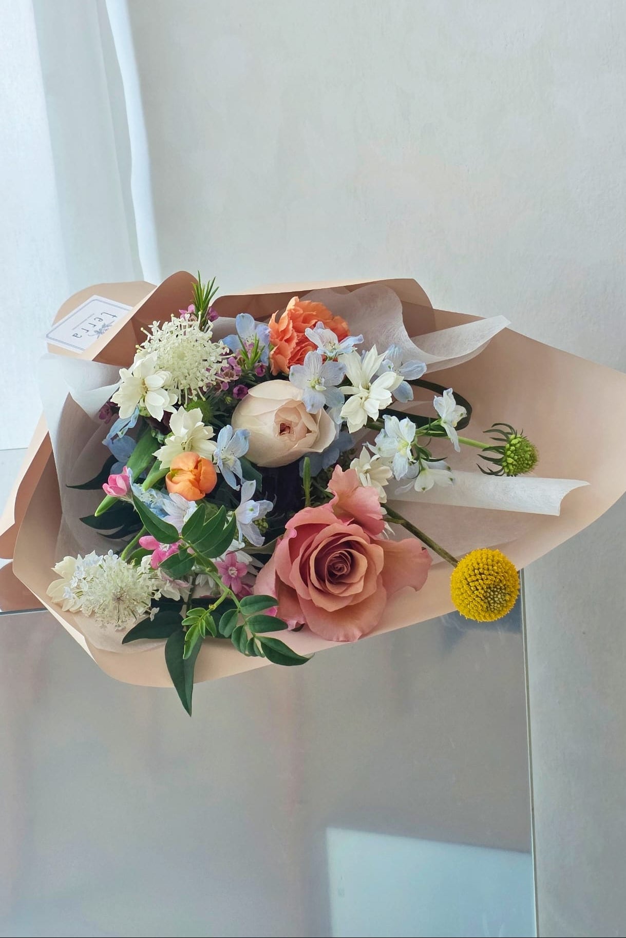 Wrapped bouquet of flowers with seasonal blooms like roses and tulips