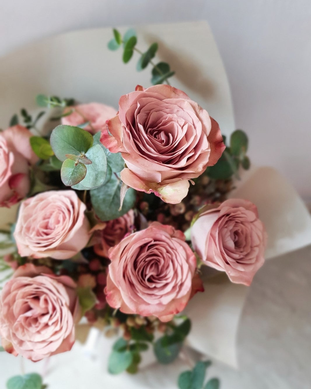 Full overhead view of The Enigmatic Muse bouquet showing cappuccino roses, Berzelia berries, trailing eucalyptus, and cream gold wrap — Flowers by Terra Singapore