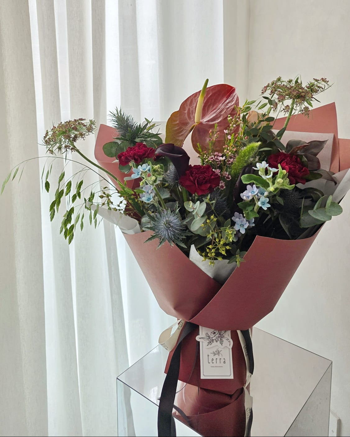 Full silhouette of a bold omakase bouquet featuring a statement burgundy anthurium, dark carnations, eucalyptus, and blue sea holly — Terra's Choice arrangement by Flowers by Terra Singapore