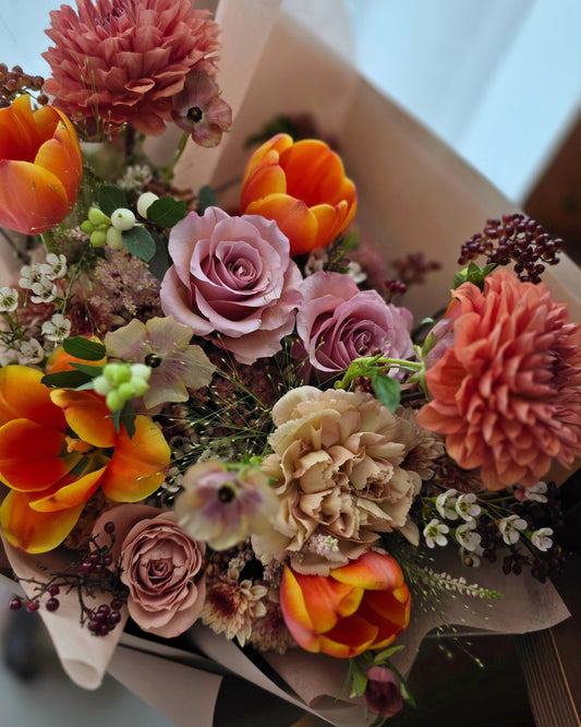 Close-up of Terra’s Choice omakase bouquet highlighting coral dahlias, peach roses, tulips and textured seasonal flowers in warm earthy tones.