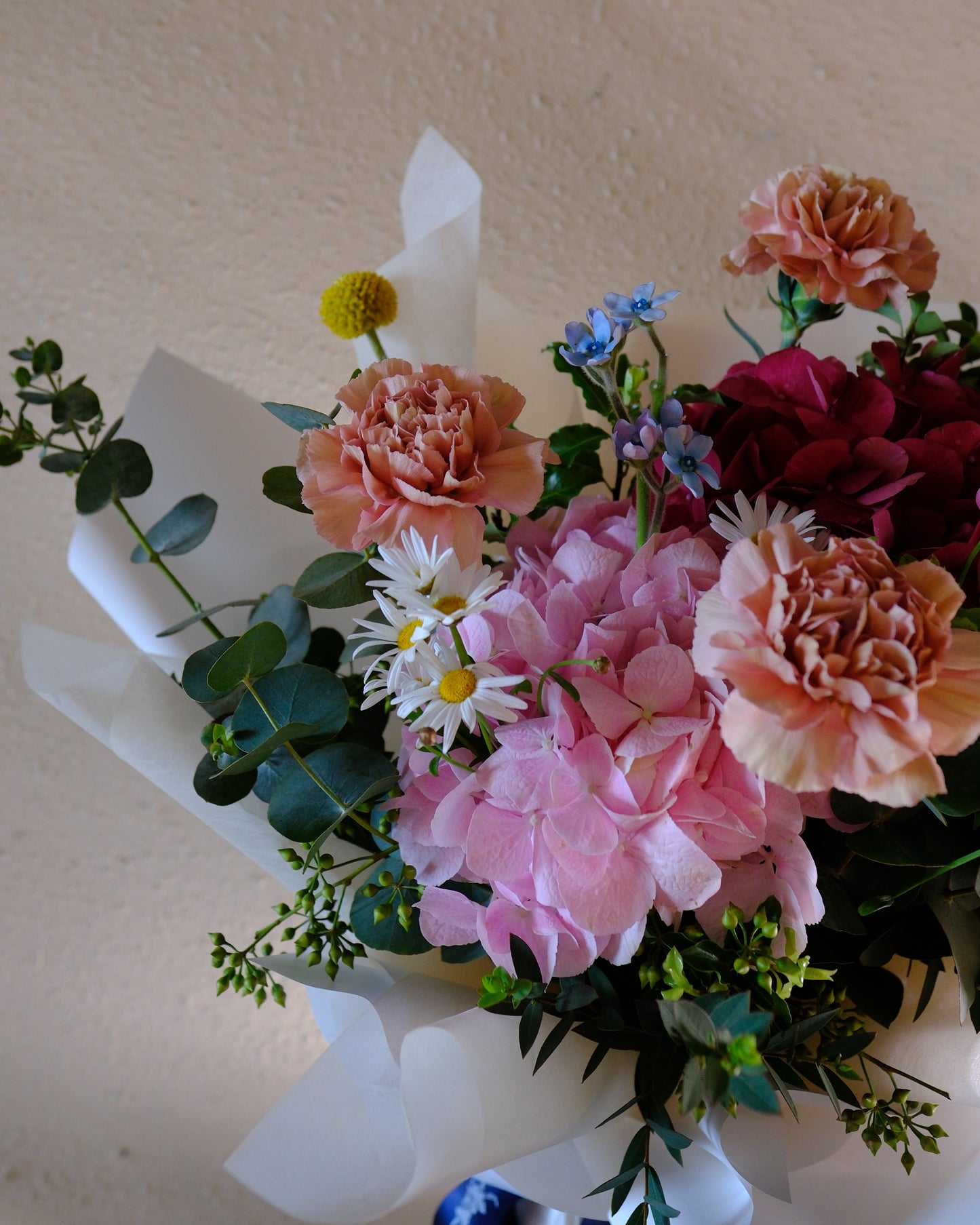 Playful and vibrant Motherâ's Day bouquet with dusty pink Dutch carnations, pink and red hydrangeas, Margarite daisies, and billy buttons designed for the fun-loving mum.