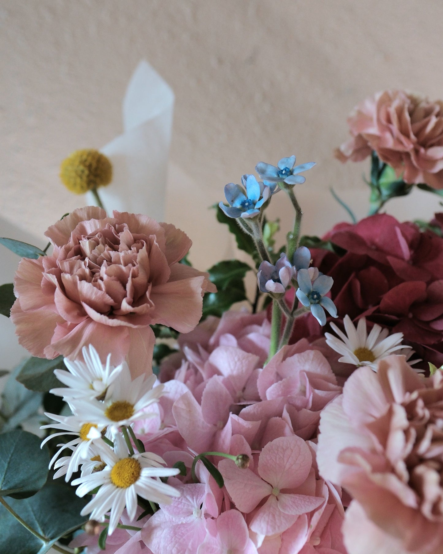 Playful and vibrant Motherâ's Day bouquet with dusty pink Dutch carnations, pink and red hydrangeas, Margarite daisies, and billy buttons designed for the fun-loving mum.