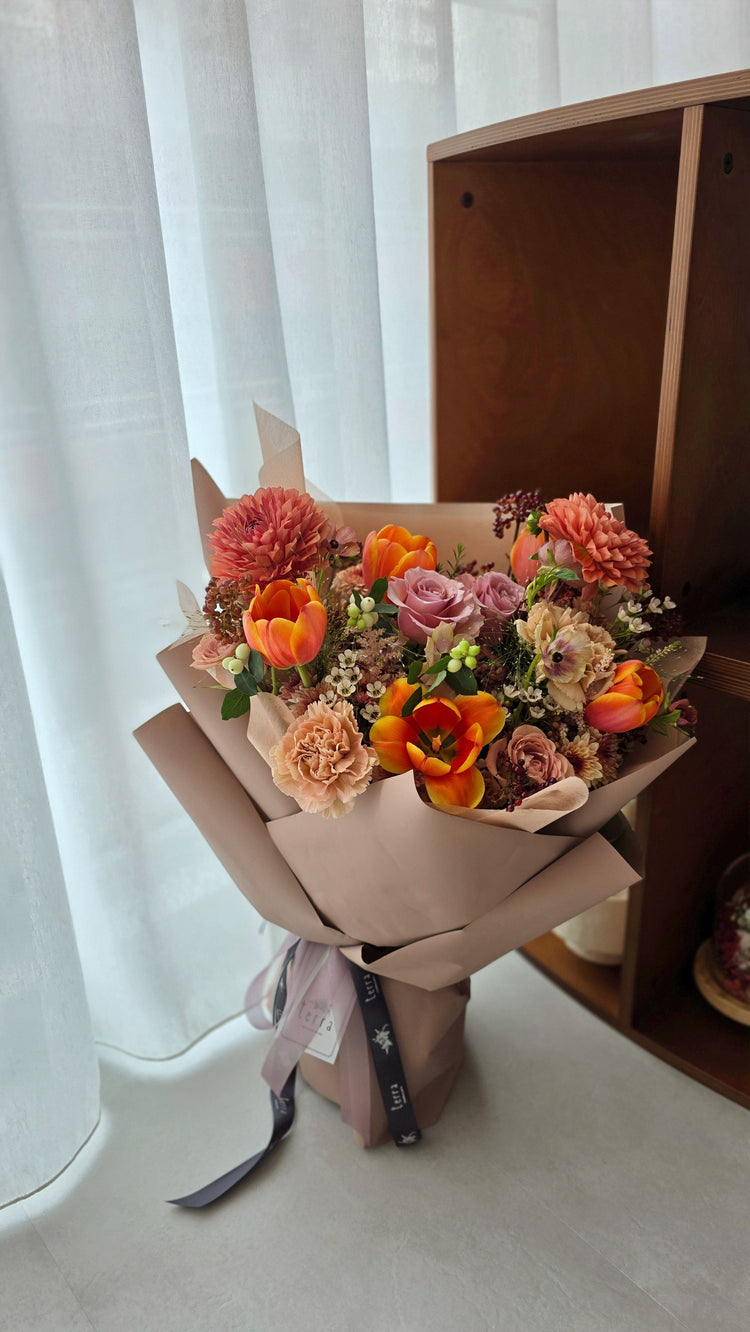 Wrapped bouquet in Coral and Autumn Colour Palette with tulips roses and dahlias