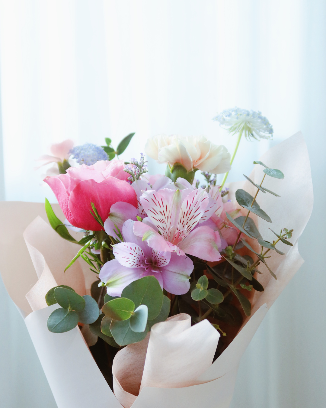 Mother’s Day bouquet with pink garden rose, blush carnations, and blue didiscus – soft, elegant, and full of natural charm.
