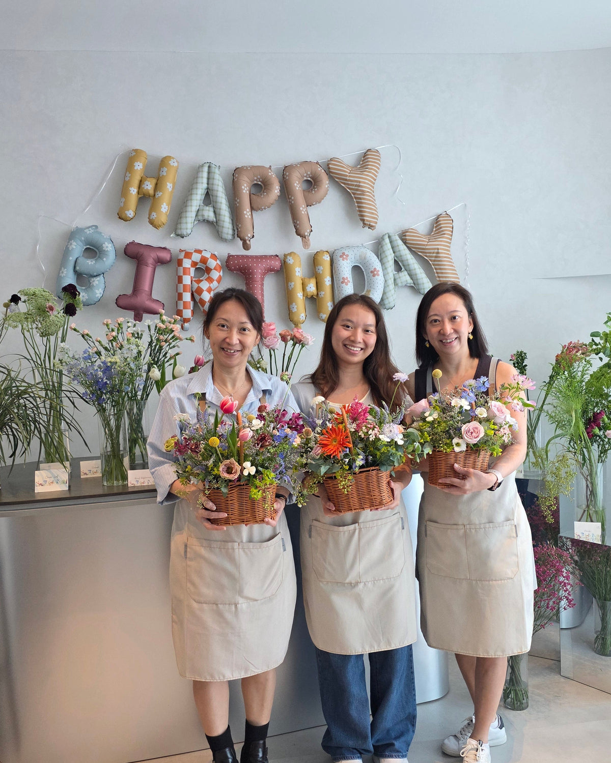 Three guests holding handmade basket arrangements at a private birthday floral party in Singapore