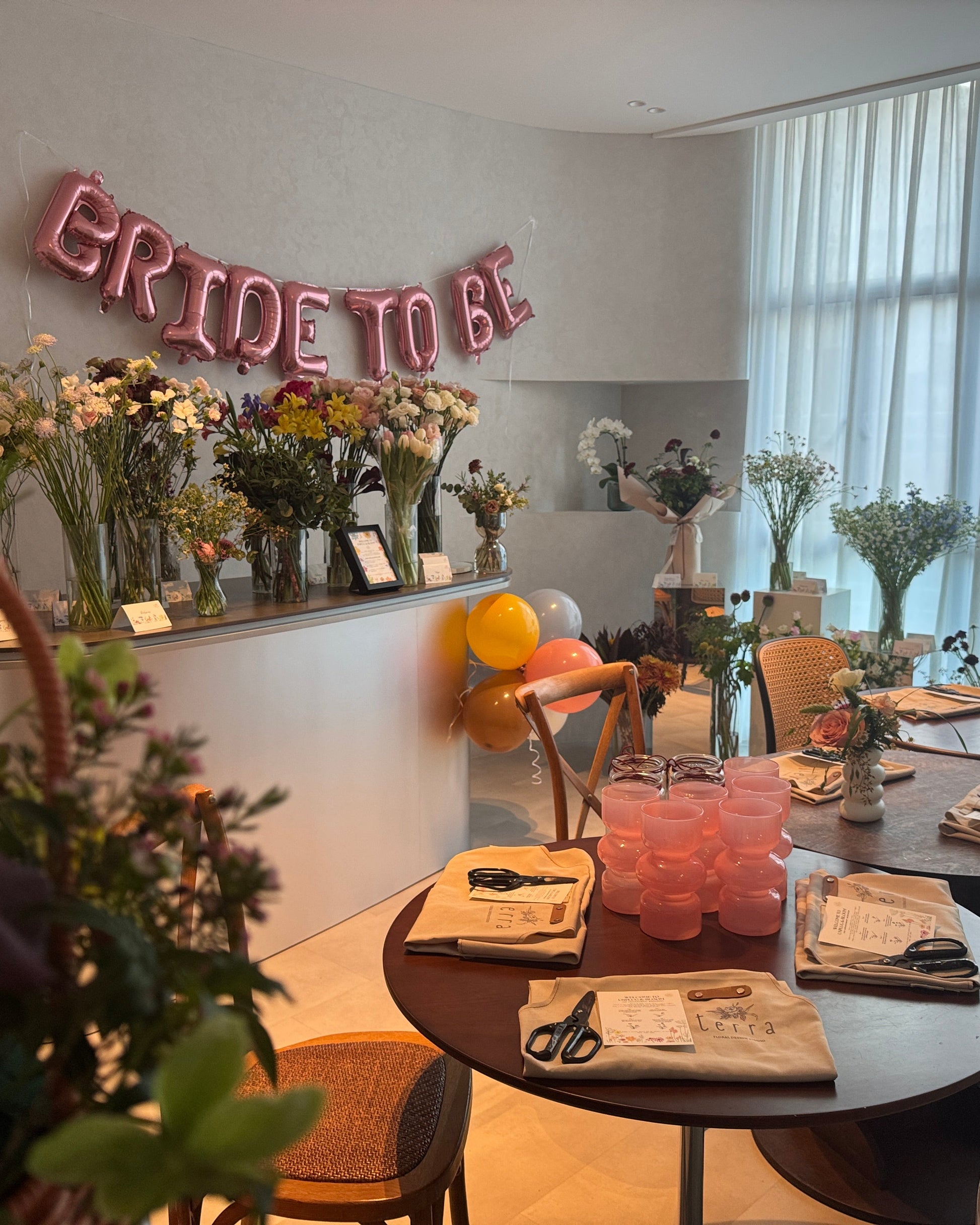 Decorated room with 'Bride to Be' balloons, floral arrangements, and tables set for a celebration.