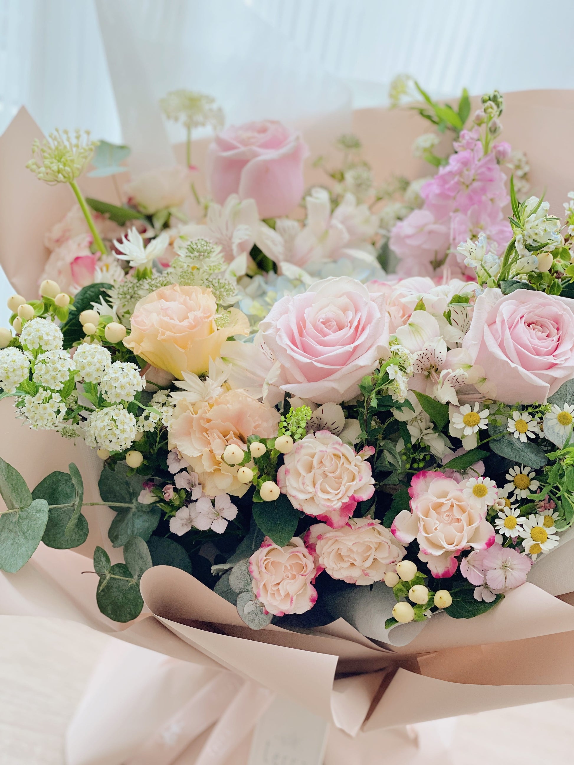 Bouquet of pink, white, and yellow flowers with greenery on a light background