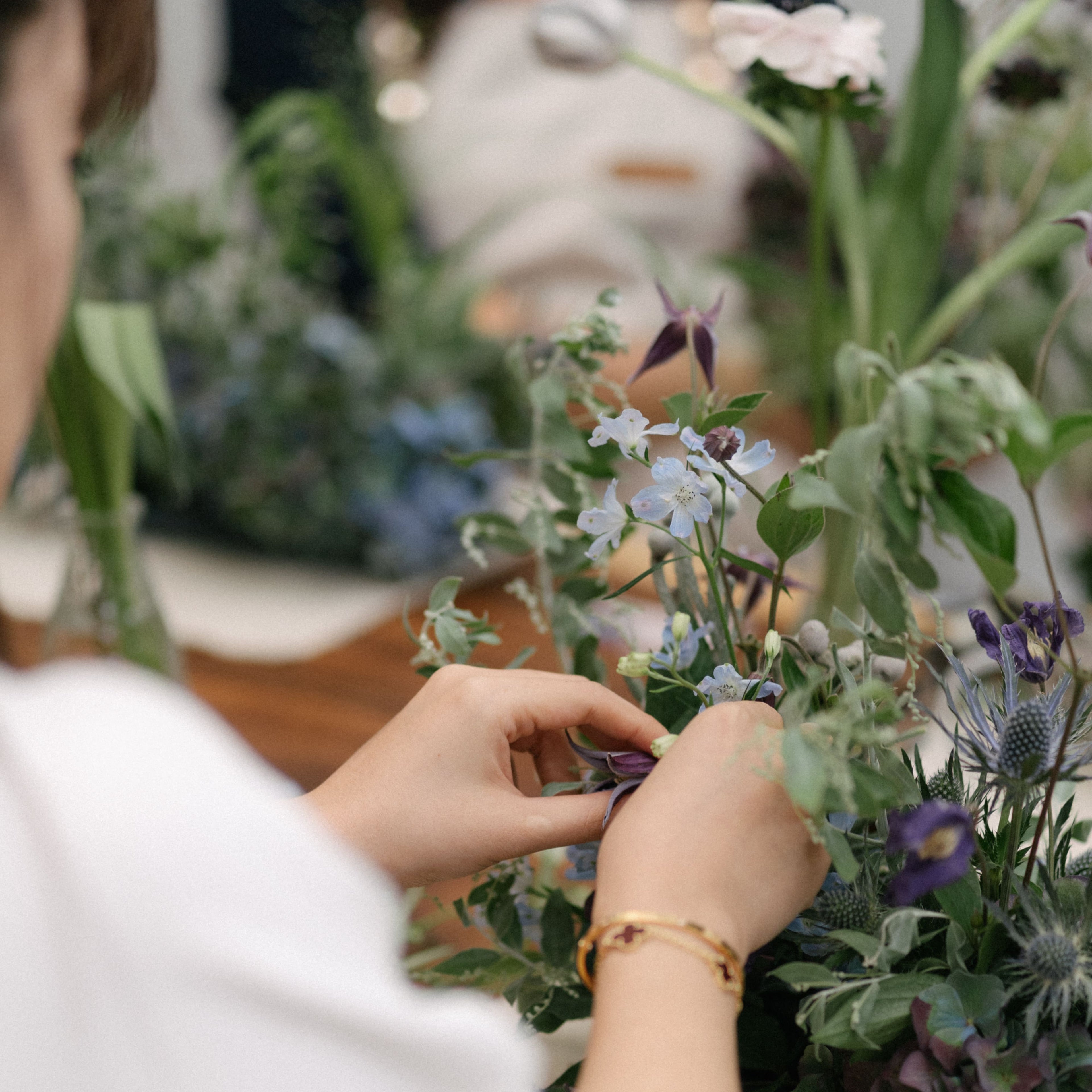 Person arranging light blue delphinium flowers in a table arrangement in a corporate team bonding class
