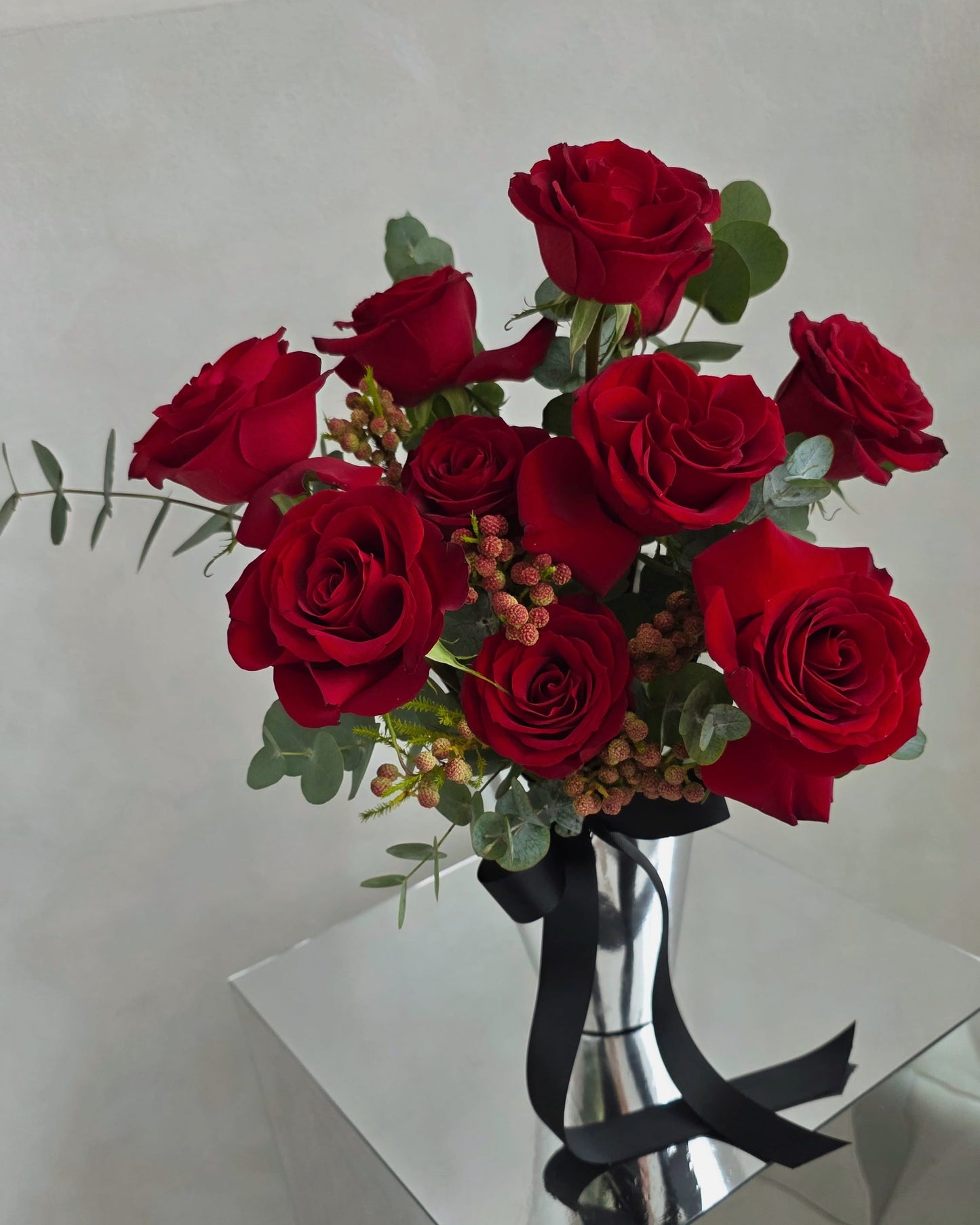 Luxury red rose vase arrangement with seasonal foliage and black ribbon, handcrafted in Singapore
