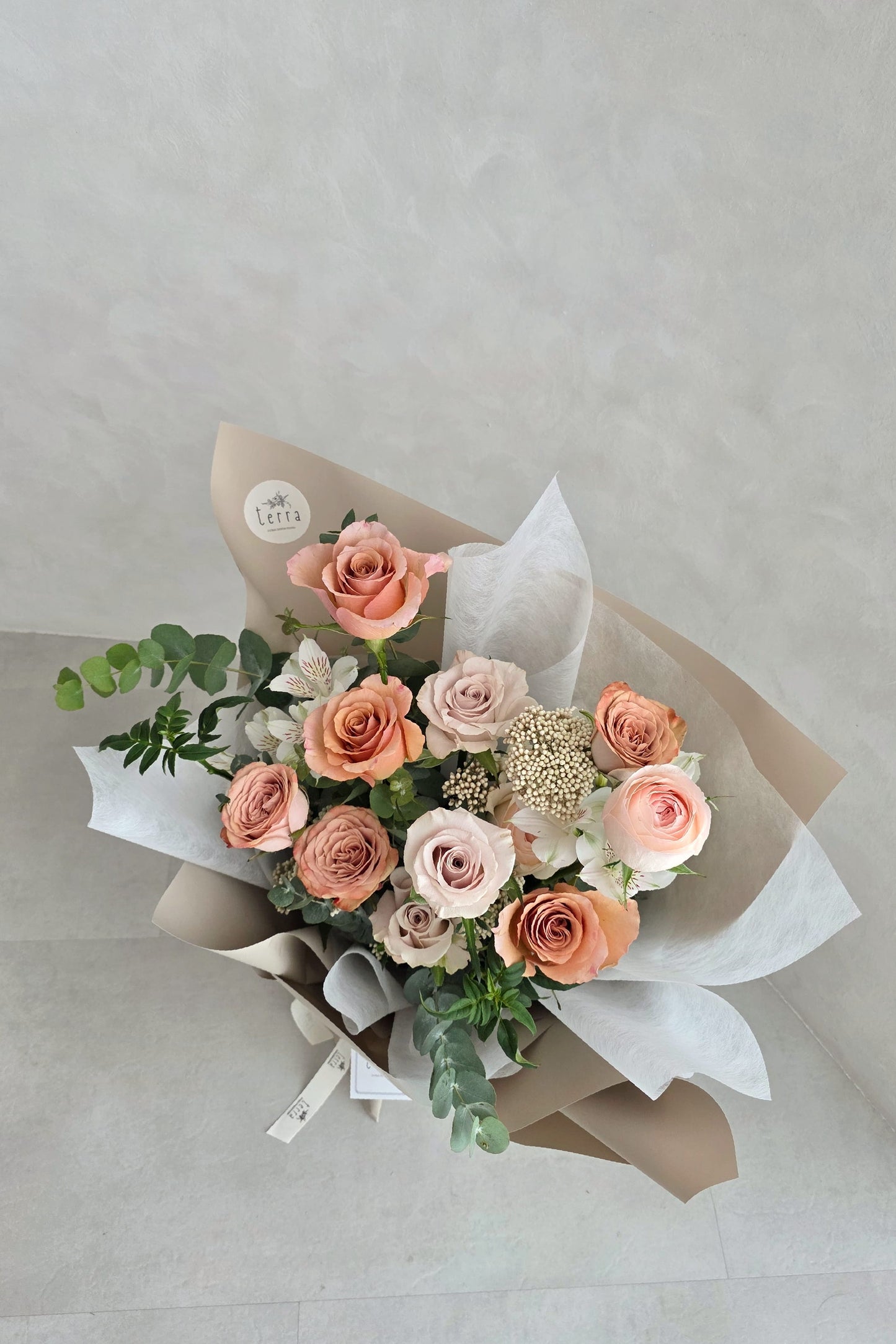 Antique Rose Bouquet by Flowers by Terra standing upright — full sand and white tissue wrap with branded ribbon and gift tag