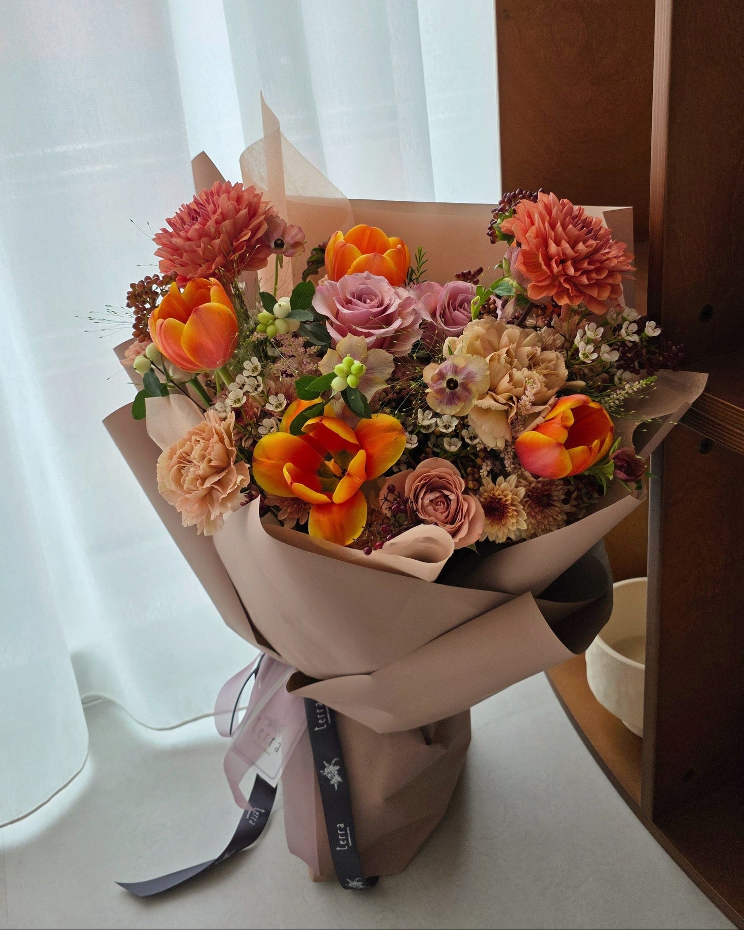 Warm earthy Terra’s Choice omakase flower bouquet styled in natural light, featuring coral and blush seasonal blooms.