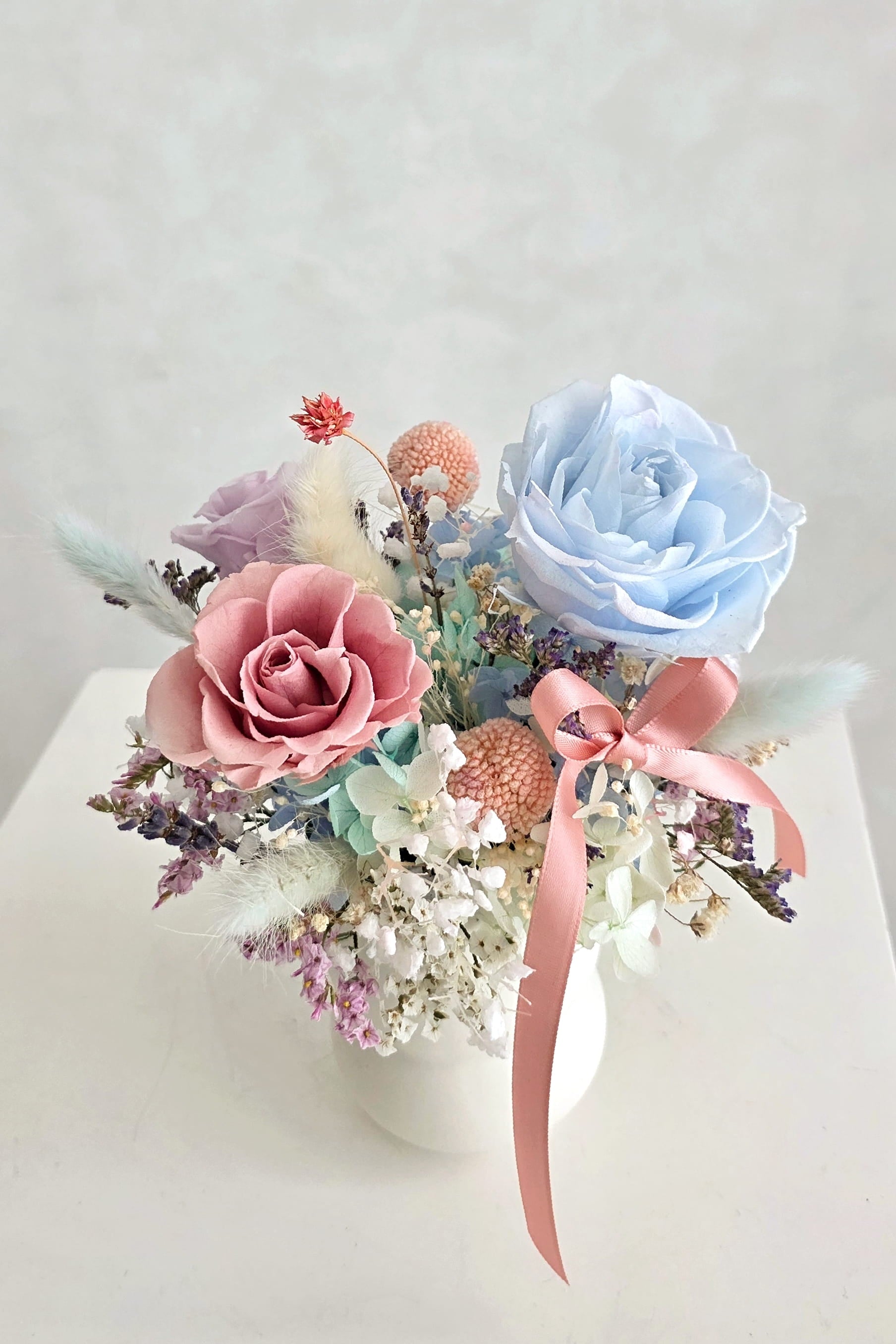 Decorative flower arrangement with everlasting preserved pink, blue, and white roses and hydrangeas 