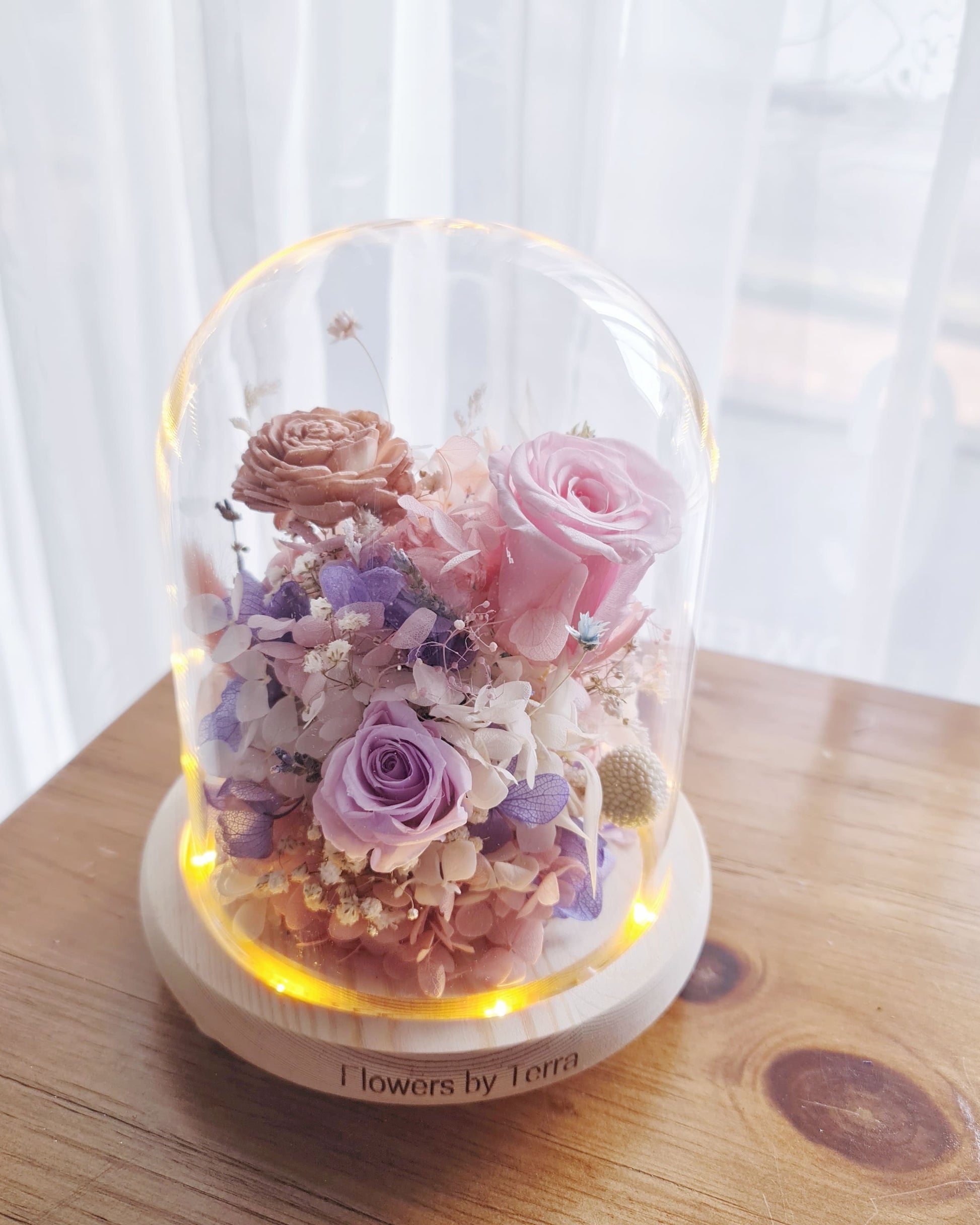 enchanté preserved flower dome lit from below with warm LED light — soft glow illuminating preserved roses and dried botanicals, Flowers by Terra Singapore